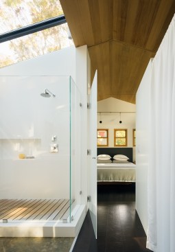 The master bed and bath in the Cow Hollow Residence feature a contiguous ceiling and floor, separated by an obscured glass swing door.