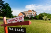 For Sale and Coming Soon realtor sign in front of large brick single family house in expansive grass yard for real estate opportunity