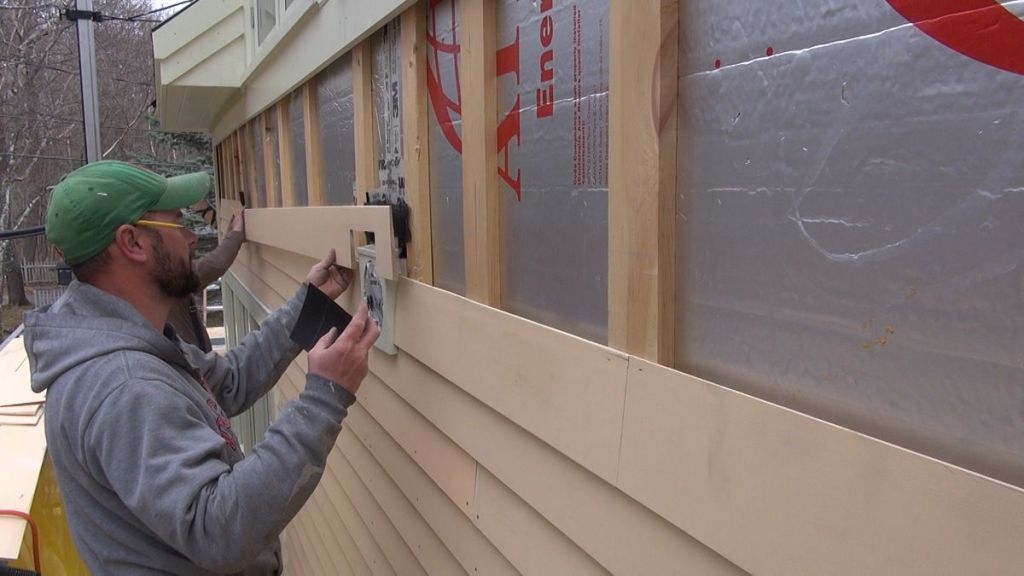 A carpenter installs a clapboard over a ventilated airspace on a wall in Maine.