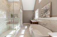 The primary bathroom in this Reading, Massachusetts, home features ample cabinet and counter space, complete with a vanity area and his and hers sinks. The property was designed by Ernest V. DeMaio at Tektoniks Architects and built by MBA Builders.