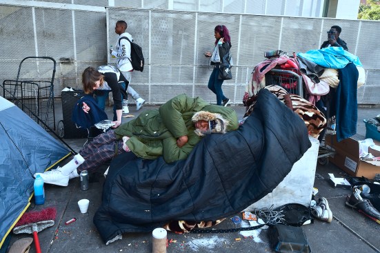 Caroline Francis places a platter of food for her fellow homeless neighbor on the street near the Los Angeles Mission.