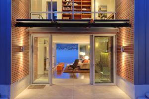 The front entry offers an alluring peek-through to serene water views on the opposite side of the house. Architect: Johnston Architects Builder: Schuchart Dow