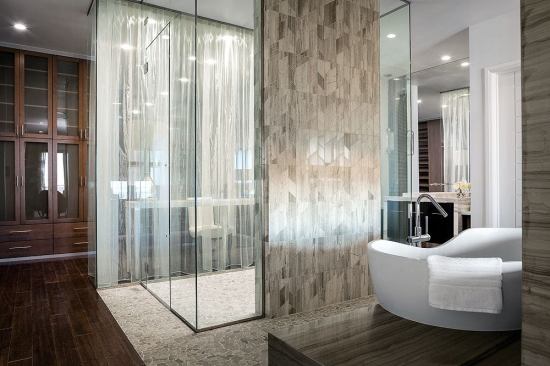The pebble flooring in the second-floor master bedroom shower runs under and beyond the shower walls to create an inlaid rug look that contrasts with the Mohawk mocha maple floors. Beyond the shower is thte dressing area with makeup table and Closet Factory storage system.