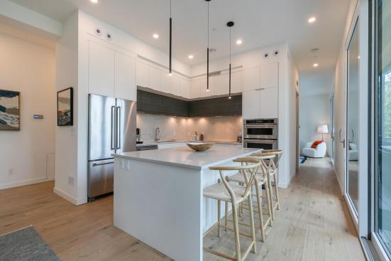 The kitchen includes a quartz-topped island, stainless steel appliances, and two-toned cabinetry.