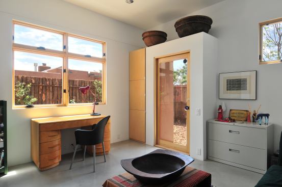 One of Browne’s budget-cutting strategies is to build the house framing to accommodate standard-sized materials such as the factory-made cabinets to the left of the door soffit, which create simple but elegant storage for the home’s wireless network setups.