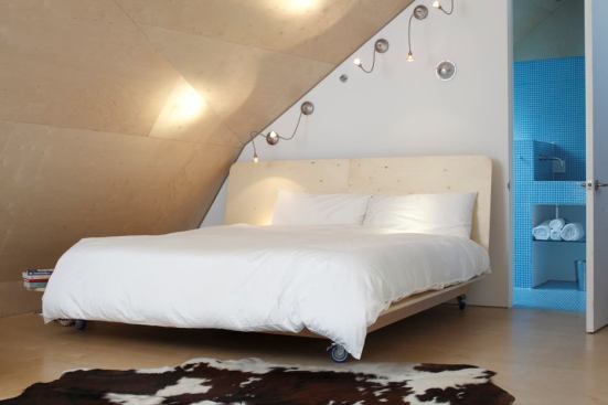 The angled wall in the top-floor master suite is clad in natural birch for a pale reflective surface that amplifies natural light throughout the room.