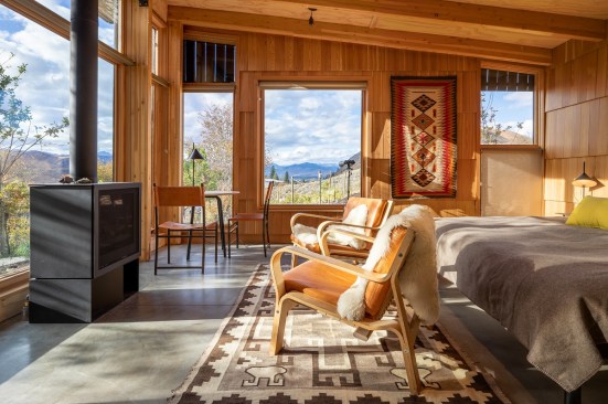 The 450-square-foot interior mirrors a quaint guest cottage with a bedroom, a wood stove, a kitchenette, storage, and a full bath.