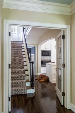 French doors in hallway open to view of stairs and kitchen entrance with dog lying on floor