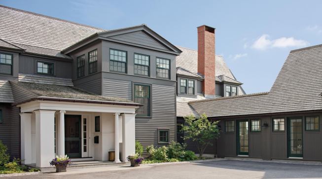The front court suggests a working dooryard. The garage wing (right) encloses the arrival court.