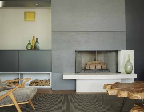 Gray cement board panels contrast with the living room fireplace's white cast concrete firebox and hearth.