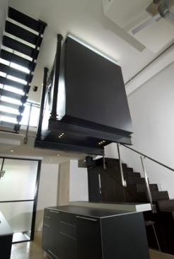 The project's wow factor and functionality impressed the judges. Like a large steel cage clad in plywood and plastic laminate, the mezzanine-level powder room (top) hangs from beams above the kitchen island. Plumbing runs under the bathroom floor to the bridge.