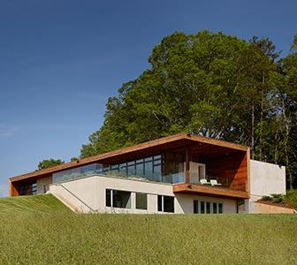 Carved into a hillside in the foothills of the Blue Ridge Mountains, this contemporary home offers expansive views of the rolling countryside. Walls of windows along the south and west fa&ccedil;ades were assembled in a custom configuration of standard windows, creating a dramatic landscape view while keeping the design economically viable. A rainwater collection system harvests 80% of the water that falls on the roof for reuse in toilets and landscaping. Project: Leicester House, Asheville, N.C.; Architect: SPC Architects, N.Y.