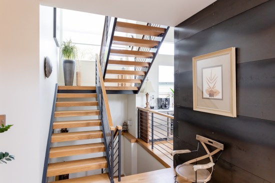 The stairs' black steel frame and white oak treads echo the white oak floors and custom-fabricated steel walls nearby.