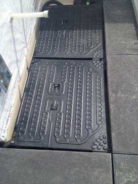 The paver can be trimmed parallel to its flow channels on either side of its inlet tubes. The pavers also can be rotated 90 degrees and use insulated flexible poly tubing to connect the rows and manifolds. The cut header channels are sealed with RTV silicone and folded over twice as a hem to create a positive seal.