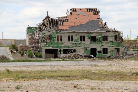 The garage doors were blown in on the walkout basement level of the South Jackson Street dentist’s office, viewed here from the vacant lot where the Greenbriar nursing home formerly stood (eleven Greenbriar residents were killed in the tornado). Underneath the dentist’s office, the concrete basement offered safety for the Huddleston family as the tornado passed.