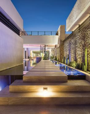 Thick stone pavers seem to float on the surface of the pool, leading to the spiral stair and a staircase down to the basement level (also accessed by the main staircase inside). Meanwhile, LED lamps from Progress Lighting highlight the rock wall and travertine step risers, just two examples of the interior and exterior lighting that serves the house and helped it achieve both NAHB Green-Emerald and LEED for Homes Platinum certifications.