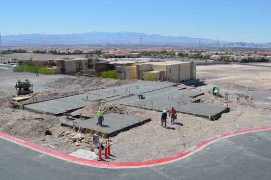 Workers smooth concrete for the foundation.