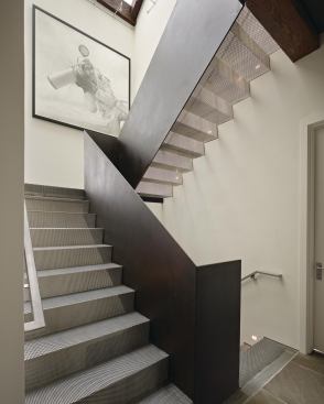 A steel plate railing provides structural support and a visual counterpoint to the semitransparent treads and risers.
