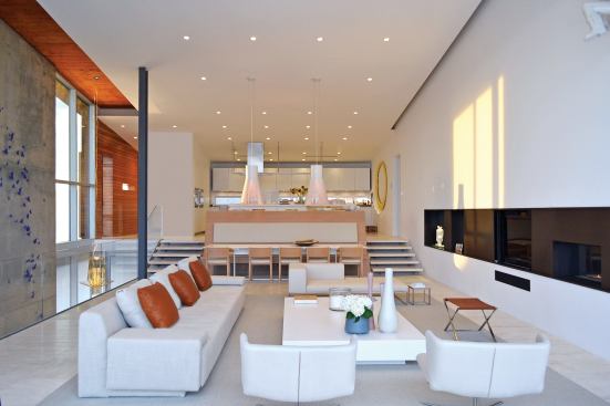 An elevated kitchen and soaring ceilings create a spacious living area, while wood finishes, travertine floors, and a butterfly speckled wall add texture.