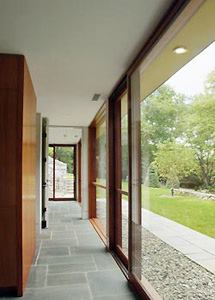 The new building continues the old house's strong relationship to the outdoors and uses radiant heat, bluestone floors, and lots of glass, just like its predecessor.