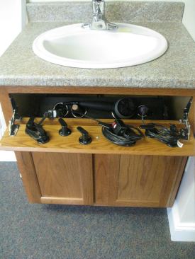 A spot in the often-unused space behind the fake drawerfront in bathroom cabinetry provides storage for hair care appliances.