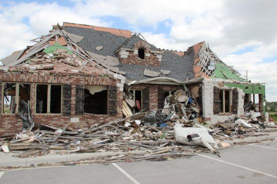 The majority of the first story framed walls and the roof of this commercial structure, a dentist office built only two years earlier, remained standing after the tornado. Many nearby older buildings collapsed, with significant loss of life. This structure was built to a more modern code edition and included structural elements required by the commercial building code, including steel connectors at every roof truss to wall connection.