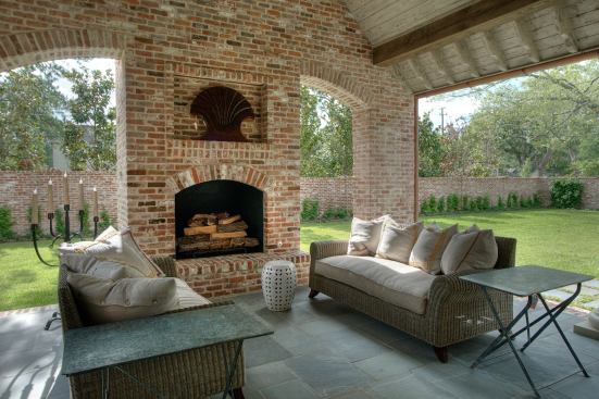 Offering a trifecta for entertaining, this bluestone and brick patio includes an outdoor living space, dining area, and food prep station sporting a built-in grill, concrete countertops, and a fridge. And with its hearth and covered seating area, the space stays functional all year long. Project: Little Lisa, Houston; Builder: Thompson Custom Homes, Houston; Architect: Robert Dame Designs, Houston; Interior designer: Kalista White Design, Houston