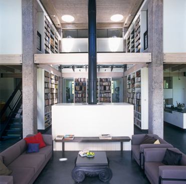 The bookshelves float between existing concrete columns forming the only rectilinear space within the water tower's curved walls.