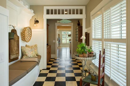 A long, wide hallway connects the garage to the kitchen. Glass panels on the inside of the arched frame make this corridor appear as if an open breezeway was eventually enclosed.