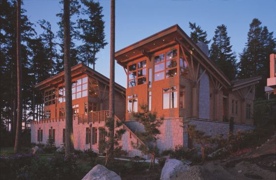 The soaring second floor of the house, clad in semi-transparentstained cedar shingles, sits atop the granitesheathed lower level.