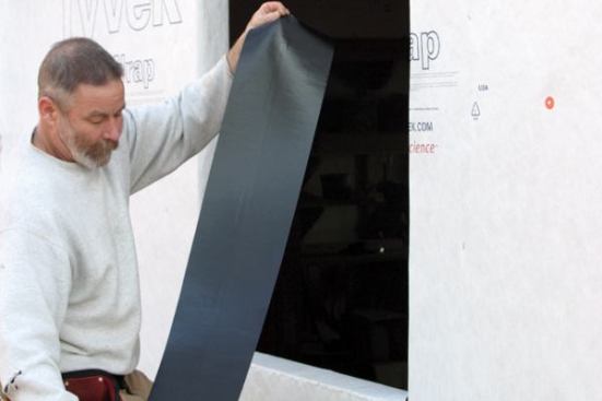 Flash the SillAfter taping the housewrap to the studs, I install the sill flashing membrane, cutting it a foot longer than the width of the opening so it can extend up the jambs 6 inches. 
Note: I prefer to use 
Tyvek FlexWrap, a butyl-based flashing membane. It has the self-healing characteristics of generic peel-and-stick but can also be stretched to form seamless corners.