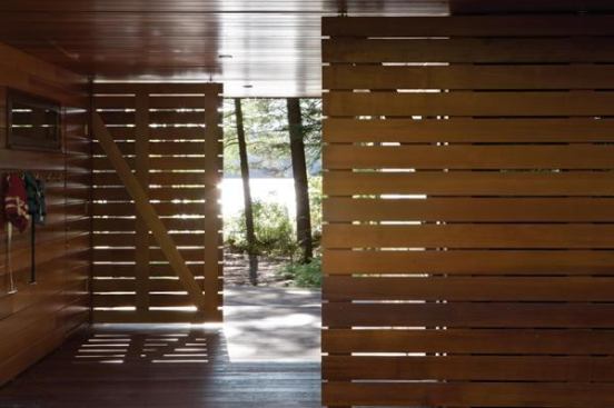 A pair of slatted barn-door style partitions allows for natural light and breezes through the back entry of this family retreat, providing a gentle transition from the main home to a trail that leads to the lake beyond.Project: Lakeside Camp, Boston area; Architect: Tom Murdough, Boston area