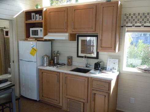 The compact kitchen features a two-burner propane stove and solid surface countertops.