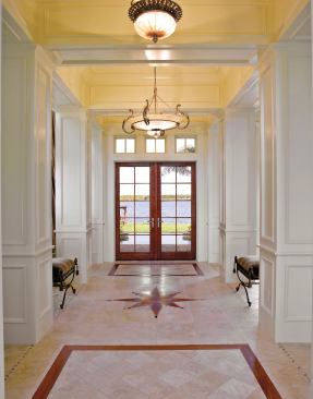 FRONT AND CENTER: A dramatic stair-tower entry opens to a center hall that leads visitors through a pair of patio doors to the pool deck and the lake beyond, exemplifying the the view-oriented, light-filled design of the entire house.