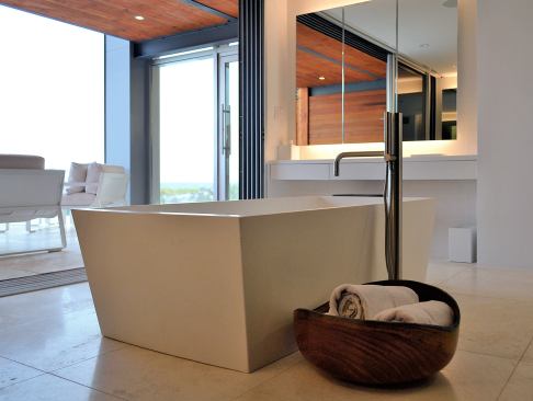 A soaking tub in the master bath permits views of the ocean. Because of the neighborhood height limit, the architects inserted a master suite in the mezzanine space adjacent to the main living area.
