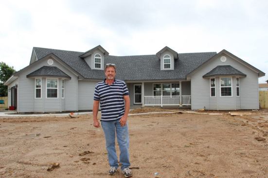 Tom Mayberry stands in front of a recently completed new home in a tornado-devastated section of the village of Duquesne, east of Joplin. Many local homeowners have chosen to wait for their turn to rebuild until a local builder has room on the schedule, rather than rush to rebuild using an out-of-town contractor.