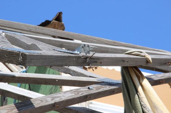 Toenails, as well as the nails in the steel connector tying this truss to the bearing wall, failed in withdrawal during the storm. Ring-shank nails or threaded fasteners might have been sufficient to prevent the failure of this connection. However, engineers generally agree that it is impractical to design wood-frame structures to resist the wind force in an F-3, F-4, or F-5 tornado.