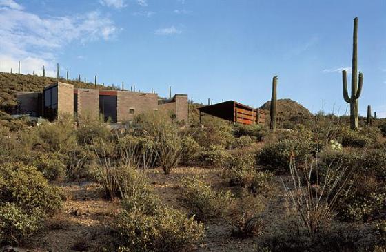 Tan masonry and rusted steel carport siding help the exterior blend into the landscape.