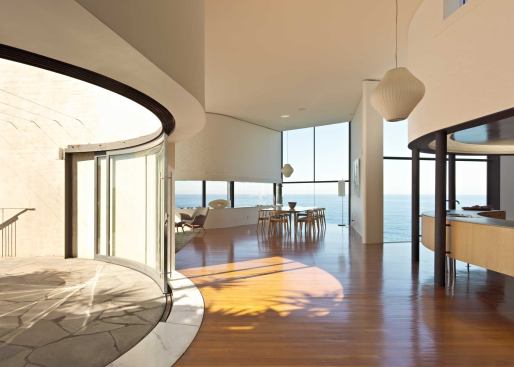 The main floor’s central living space opens onto a terrace via a set of curved sliding glass doors.