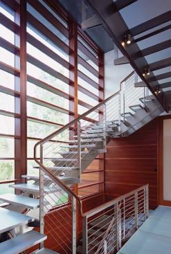 An open-riser staircase climbs past a glass wall and an exterior set of mahogany sunshades. "The house is consistent inside and outside," one judge said.