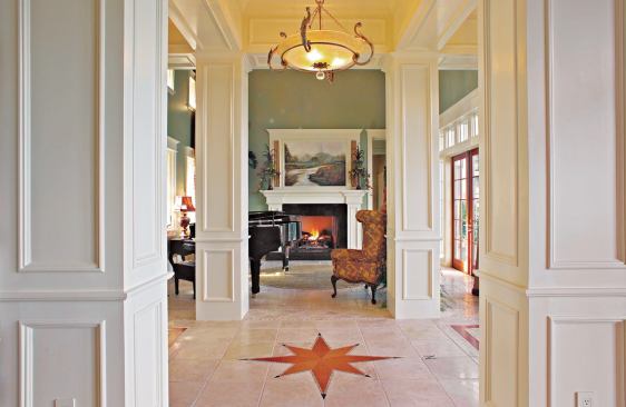 SIGHT LINE: Four columns accentuate the formality of the center hall entry to the house and separate the dining room from the parlor (shown here), a two-story space featuring a propane-fueled fireplace. Both spaces gain light from either side, especially from the trio of hinged patio doors, complete with matching sidelites and fixed clerestory windows, that expose the north elevation.