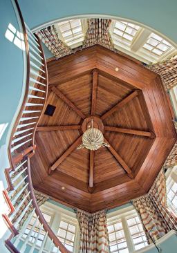 BEAMED UP: Exposed and richly stained cypress beams and paneling grace the octagonal ceiling of the stair tower, a detail repeated in the parlor that reflects the British colonial feel of the house.