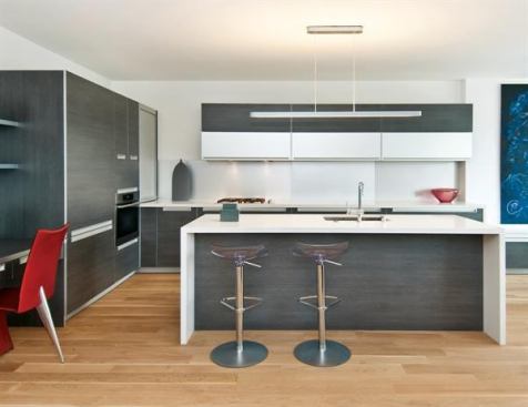For a contemporary kitchen, this sleek island offers a clean line of white quartz to contrast with the kitchen’s dark wood, aluminum cabinets, and stainless steel backsplash. Project: NOVE Kitchen, San Francisco; Builder: Linea Built, San Francisco; Architect: Handel Architects, San Francisco.