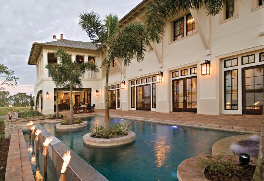 THE LIFE AQUATIC: The legnthy pool terrace, accessed at several points from every room along the back of the house, features a playful pool. Water that splashes over the disappearing edge flows into a trough sporting gas-fired tiki torches that add even more visual interest.