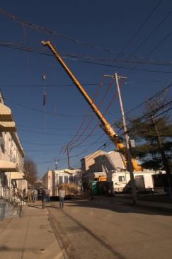 Lined Up. Raising modules to set them onto a site within an existing neighborhood calls for big equipment that often must navigate obstacles like power lines and utility poles.