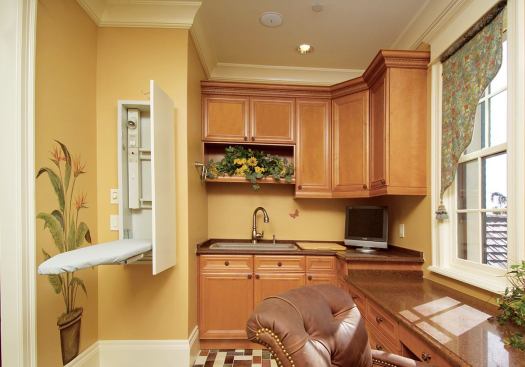 INDEPENDENCE TEST: With a deep sink and an undercounter fridge, a pair of desk/craft areas, and a full-size laundry equipment supplemented by a cabinet-concealed ironing board, the second-floor laundry/hobby room is a testing ground for adult independence.