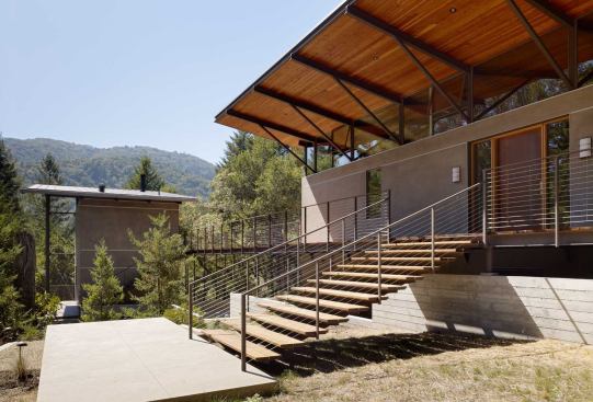 The deck runs the full length of the main house, bridging the driveway to reach the guest house.