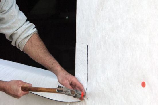 The flashing has a memory, so to prevent it from curling back, I drive a cap nail at the outer edge to hold it in place until the adhesive cures (24 to 48 hours).