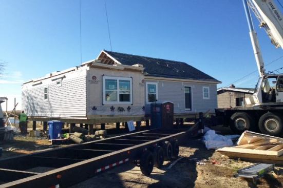 Modular houses are constructed at a factory and then delivered to the jobsite, where they are craned into place.