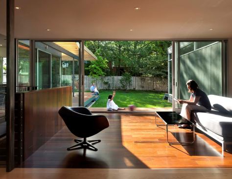 The flat roof cantilevers out beyond the walls to shade disappearing glas doors.